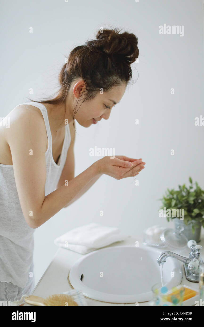 Young attractive Japanese woman washing face in the bathroom Stock Photo