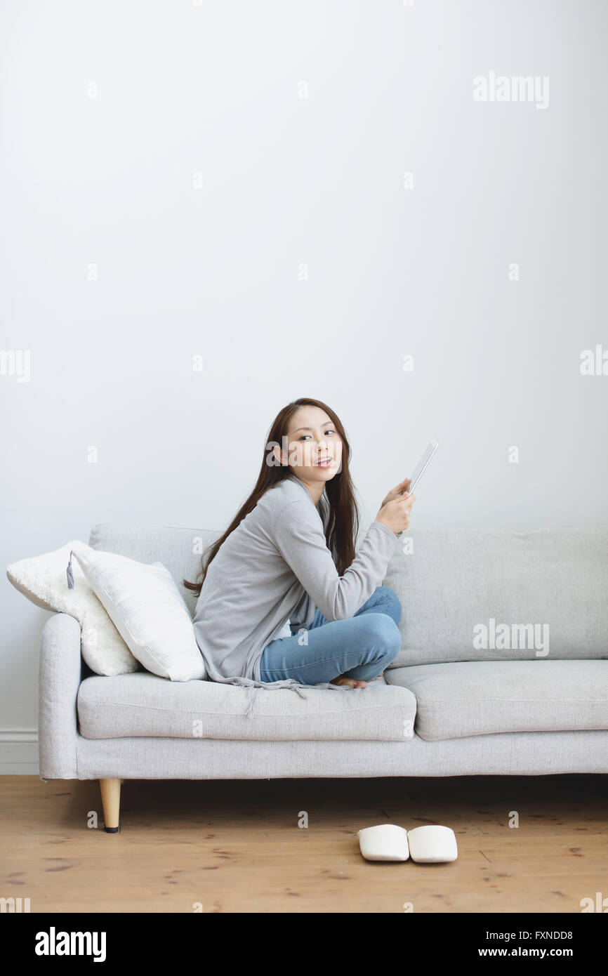 Young attractive Japanese woman with tablet on the sofa Stock Photo - Alamy