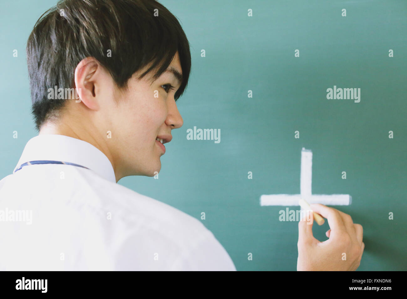 Japanese highschool student writing on classroom blackboard Stock