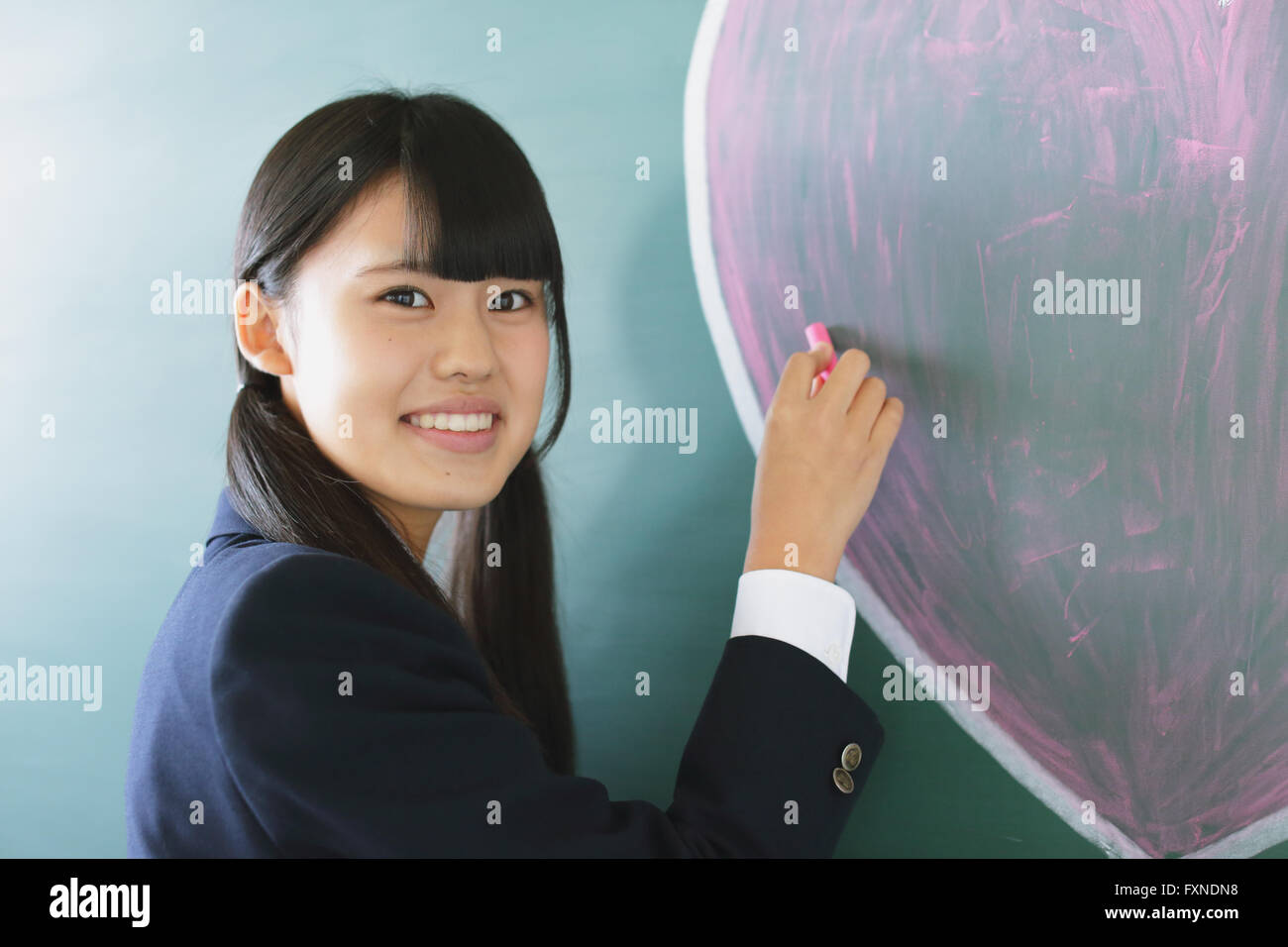 Japanese highschool student writing on classroom blackboard Stock