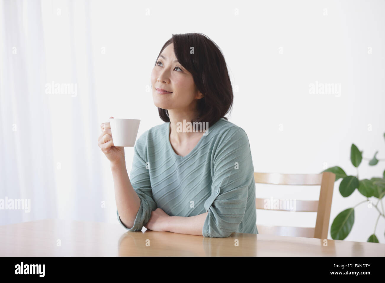 Senior Japanese woman having coffee in the living room Stock Photo