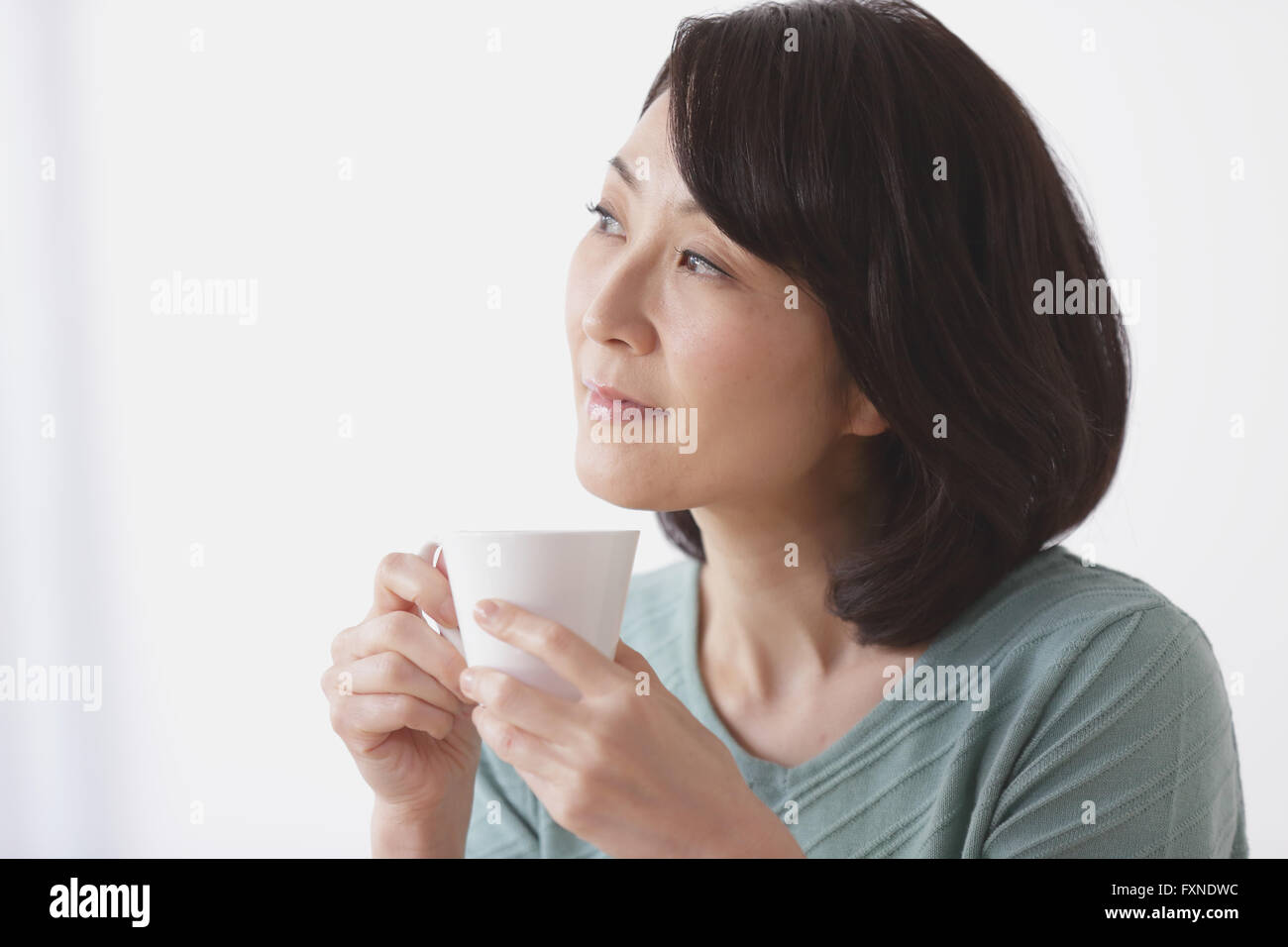 Senior Japanese woman having coffee in the living room Stock Photo