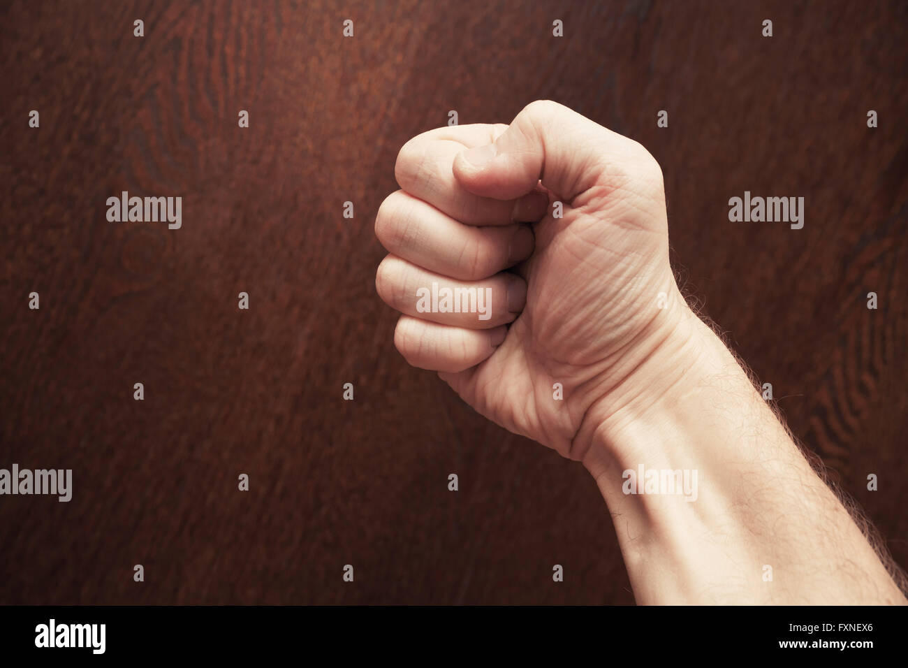 Strong male fist over dark brown wooden background Stock Photo - Alamy