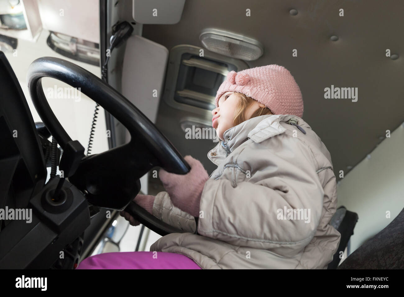 Cute Caucasian baby girl driving big cargo truck, closeup photo Stock Photo