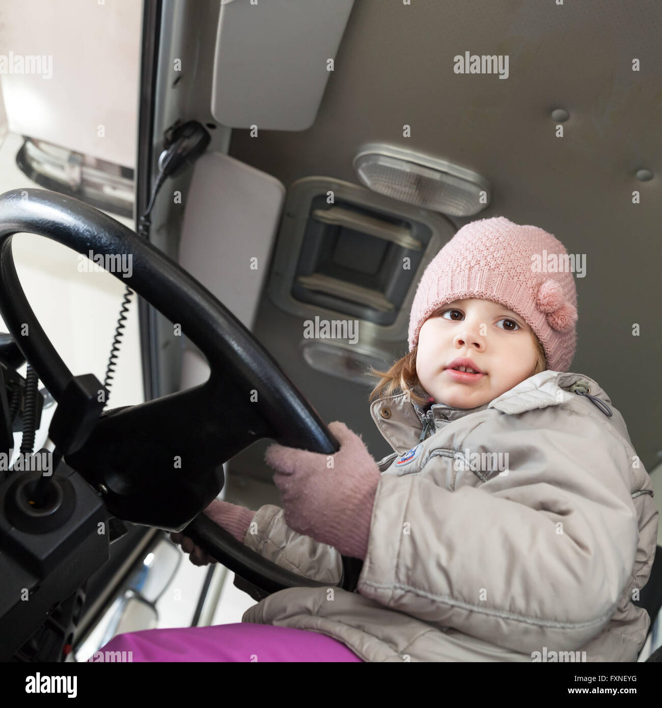 Cute Caucasian baby girl driving big cargo truck, square photo Stock Photo