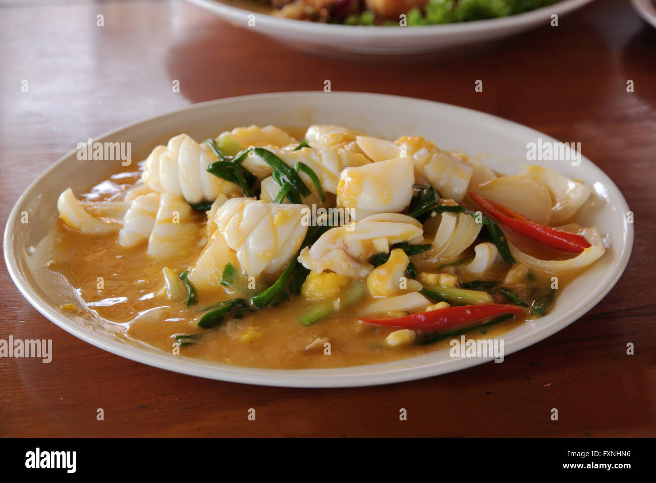 Stir fried squid with salted eggs on wood table Stock Photo