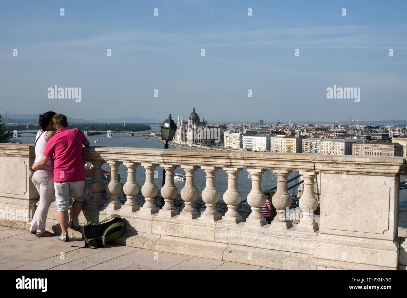 Visitors admire the view of the River Danube and in the distance is the Hungarian Parliament from the Danube terrace on Buda C Stock Photo