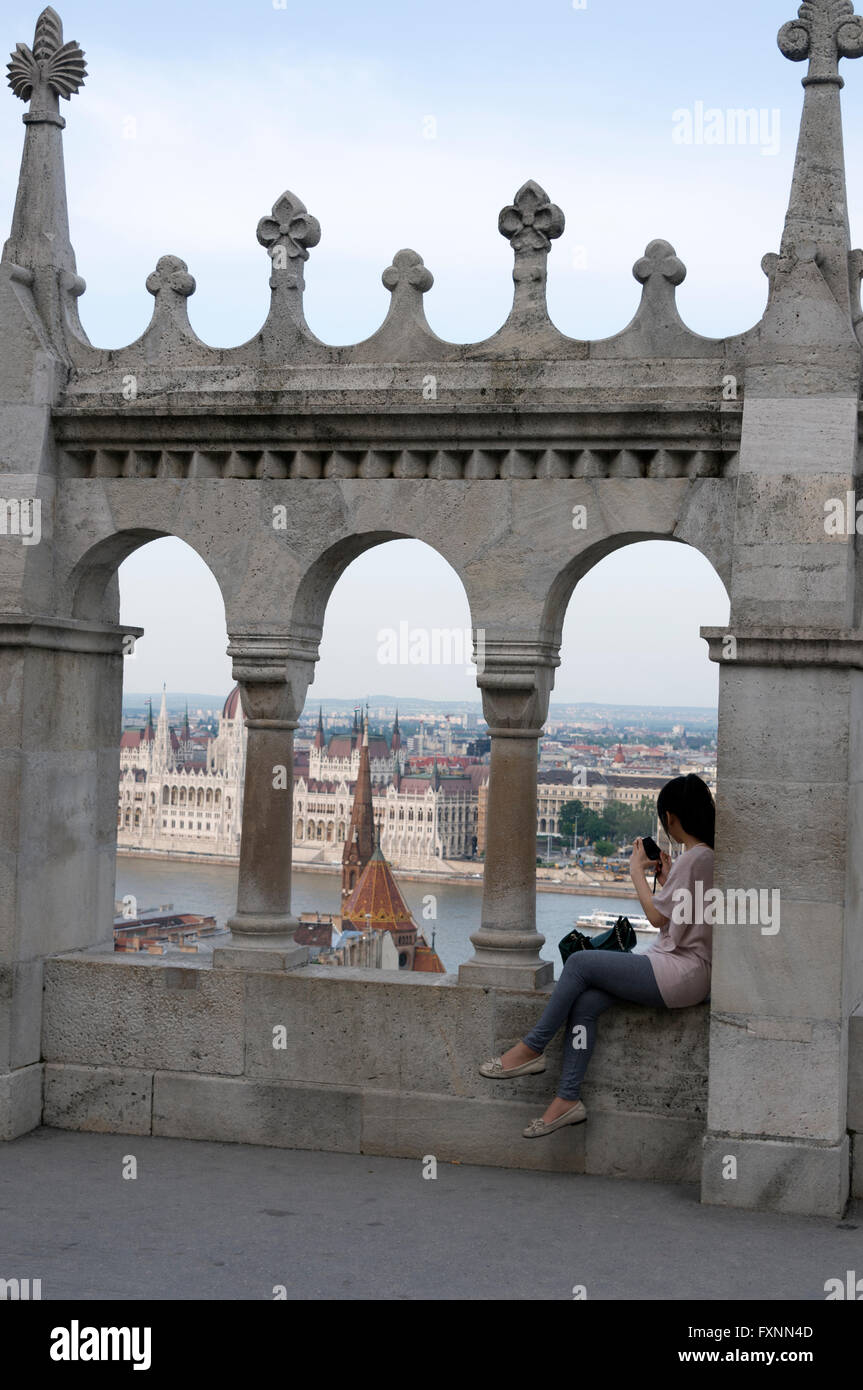 A young Asian tourist admires the city view from the Fishermen's Bastion at Buda Castle hill in Budapest, Hungary.  Buda Castle Stock Photo
