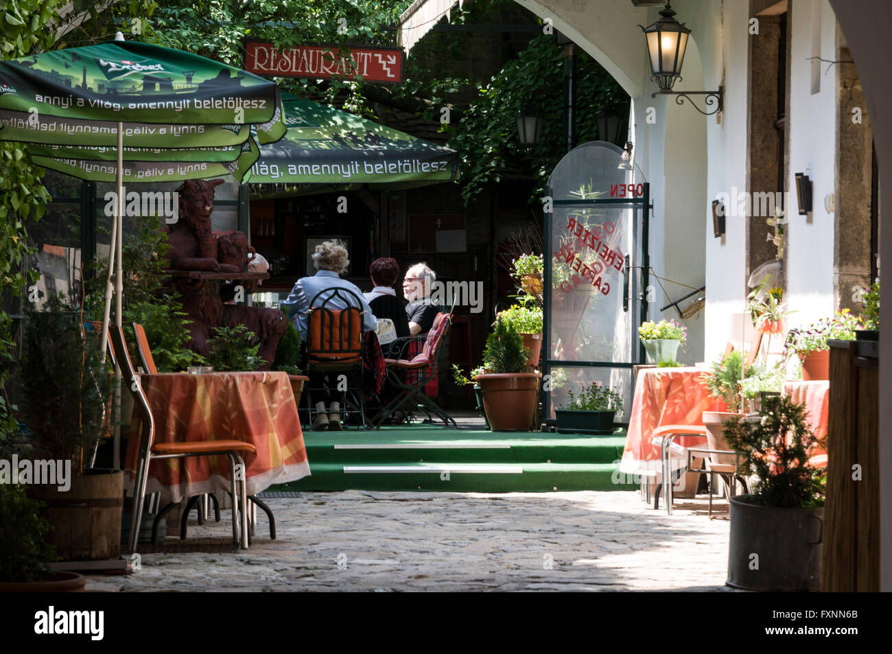 Guests enjoying a lunch in an open courtyard of a small outdoor restaurant in the Buda Castle Hill district of Budapest in Hunga Stock Photo