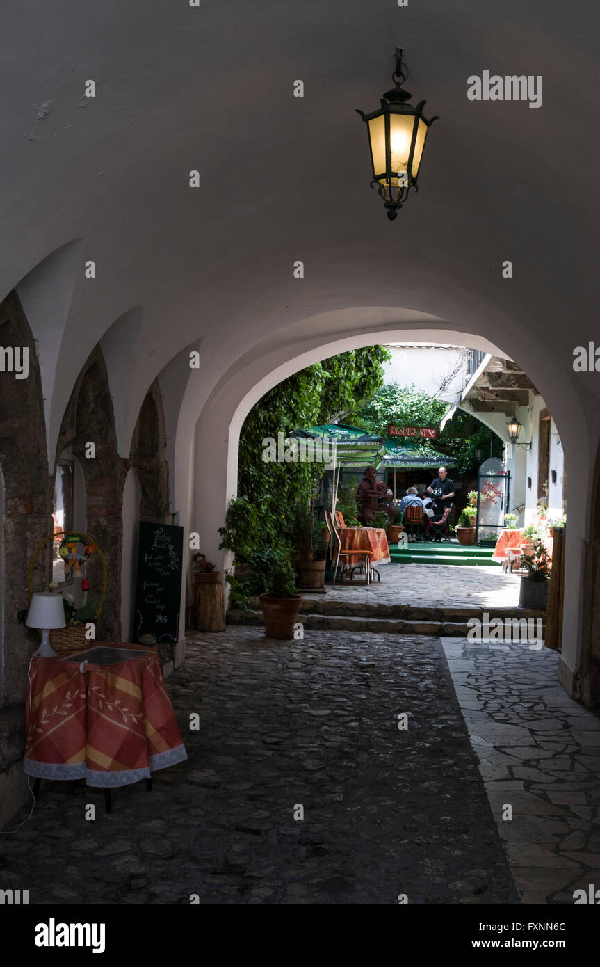A long archway leads into a small courtyard restaurant in the Buda Castle Hill district of Budapest in Hungary. Buda Castle H Stock Photo