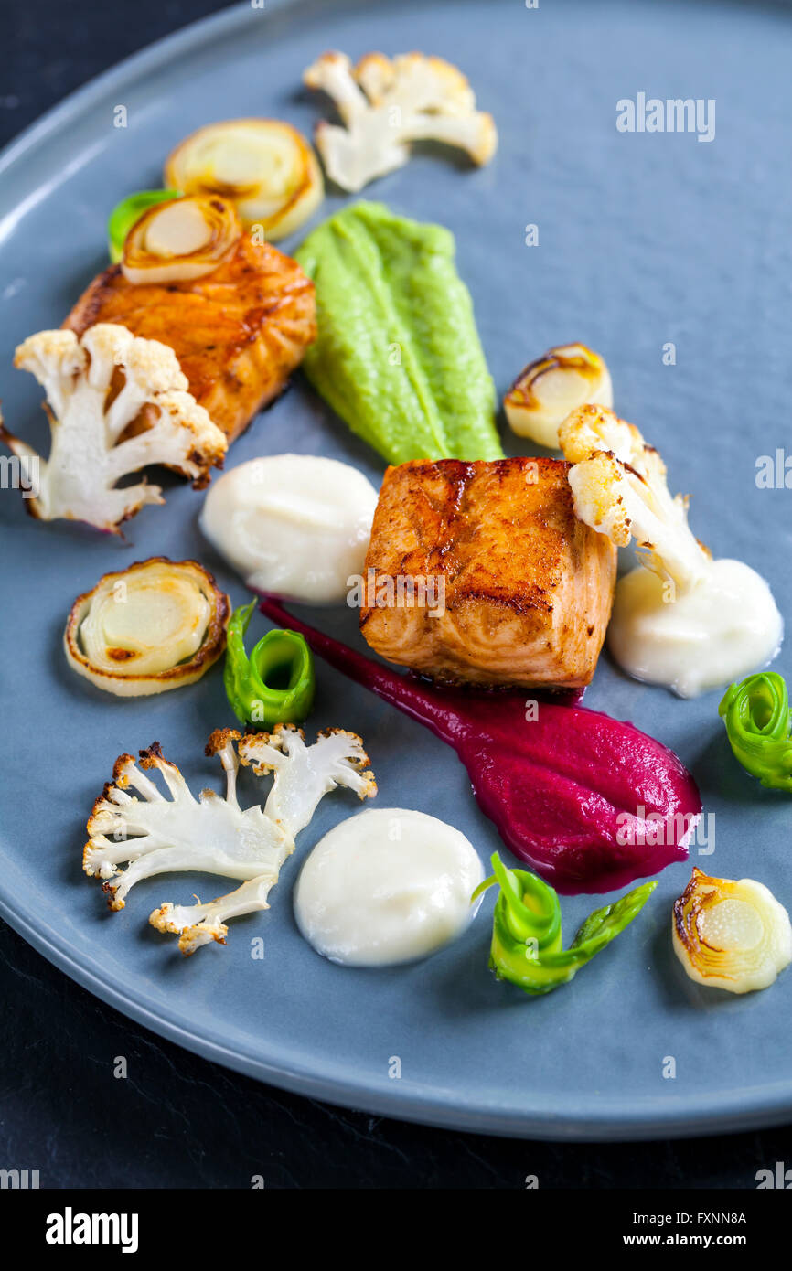 Pan fried salmon, pea puree, beetroot puree, cauliflower and asparagus ribbons Stock Photo