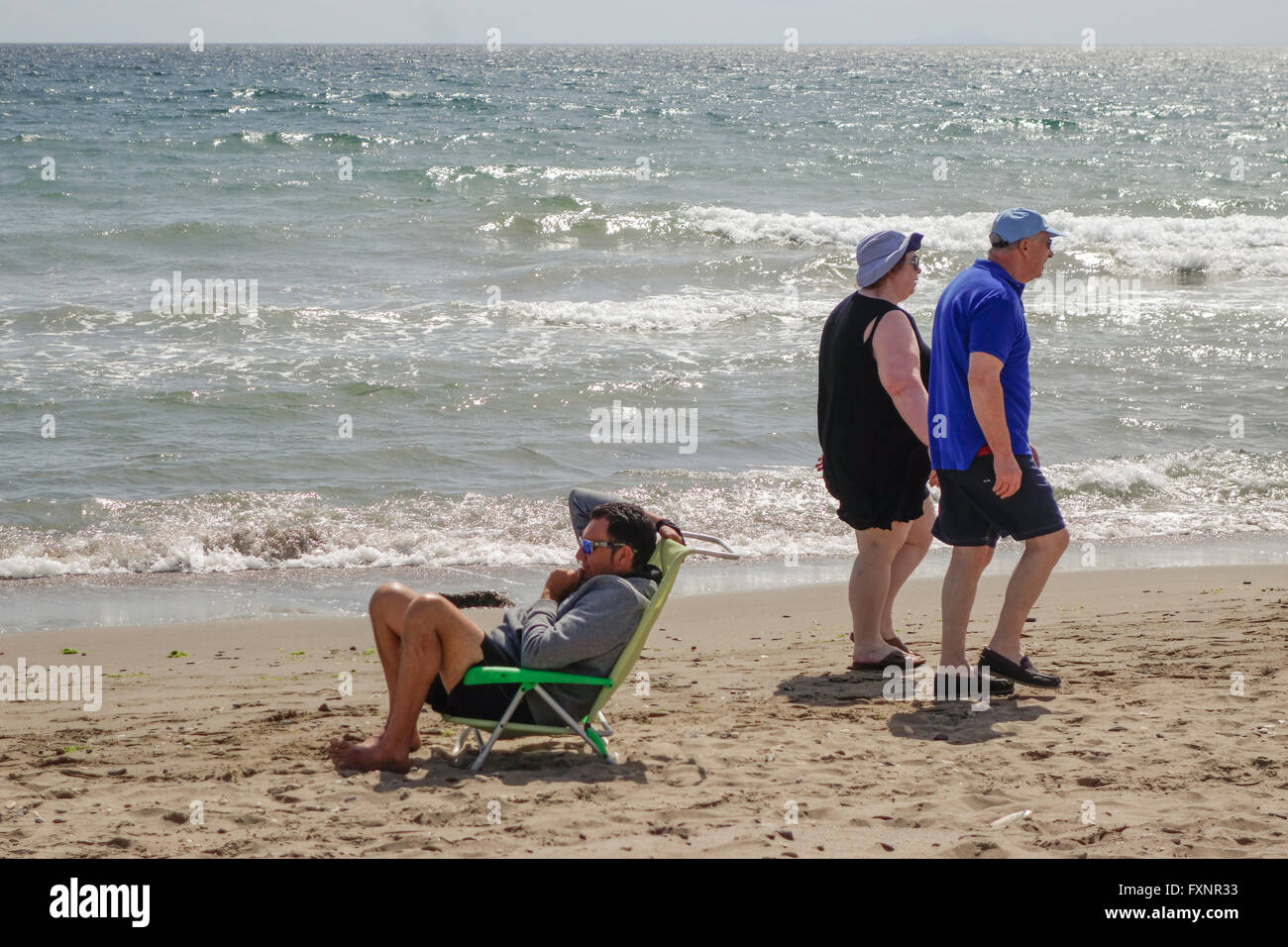 Older couple taking a stroll along the beach in Spain, during clouded weather. Andalusia, Spain. Stock Photo