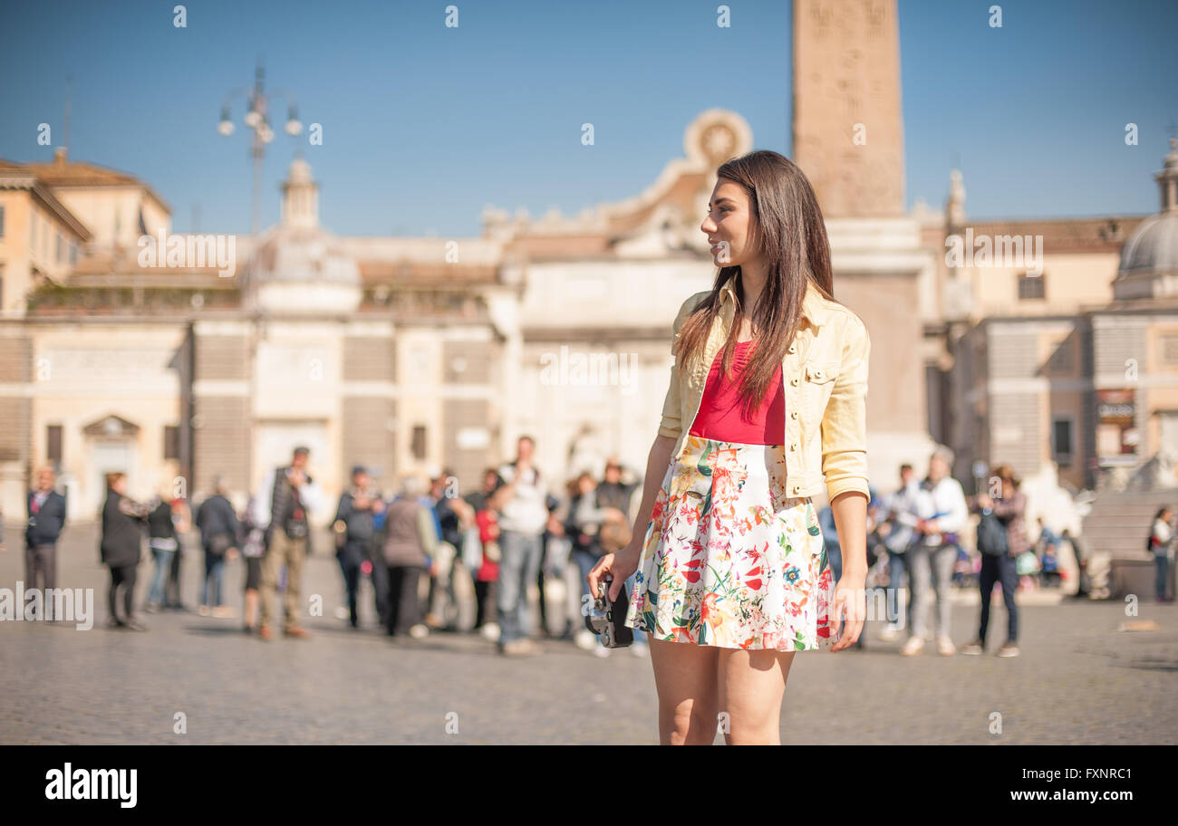 Young tourist woman in Rome smiling looking at the place, many people in background Stock Photo