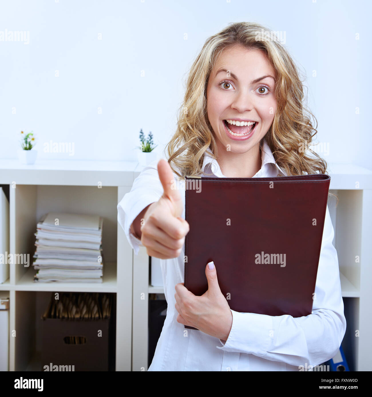 Female happy job candidate with CV holding her thumbs up Stock Photo