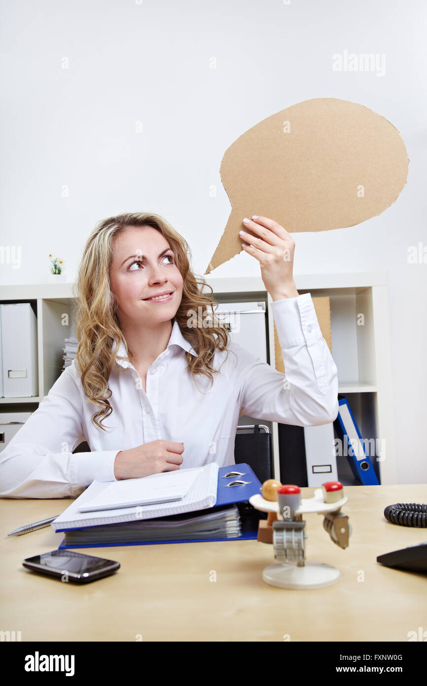 Attractive blonde woman holding empty speech balloon in the office Stock Photo