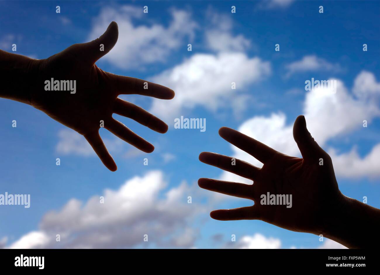 Silhouette of two hands reaching towards each other. Stock Photo