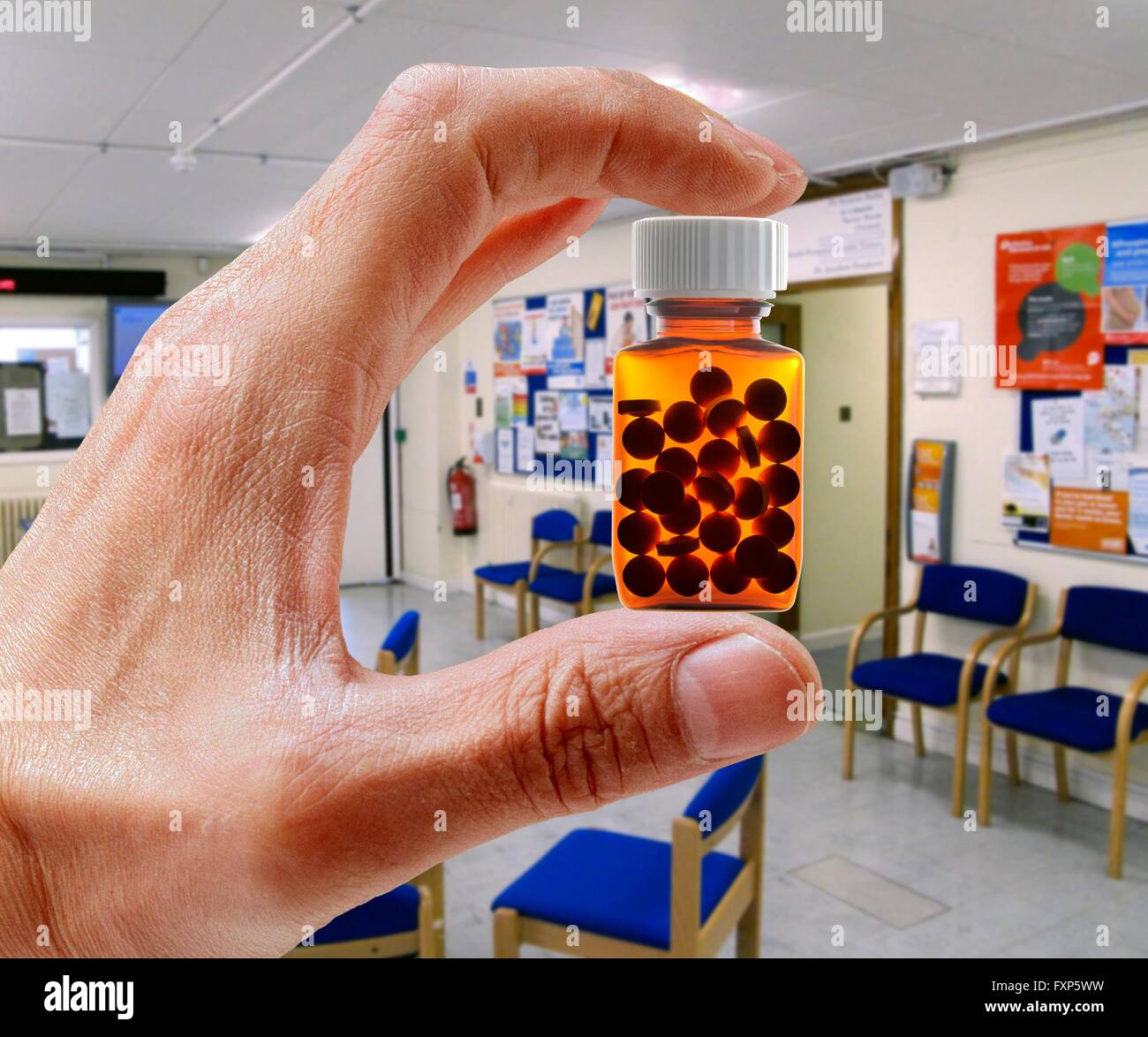Hand holding pill bottle in waiting room. Stock Photo