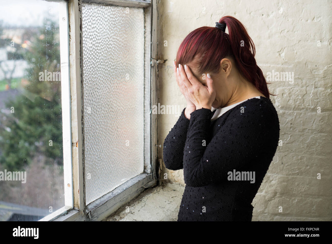 Woman crying by the window Stock Photo
