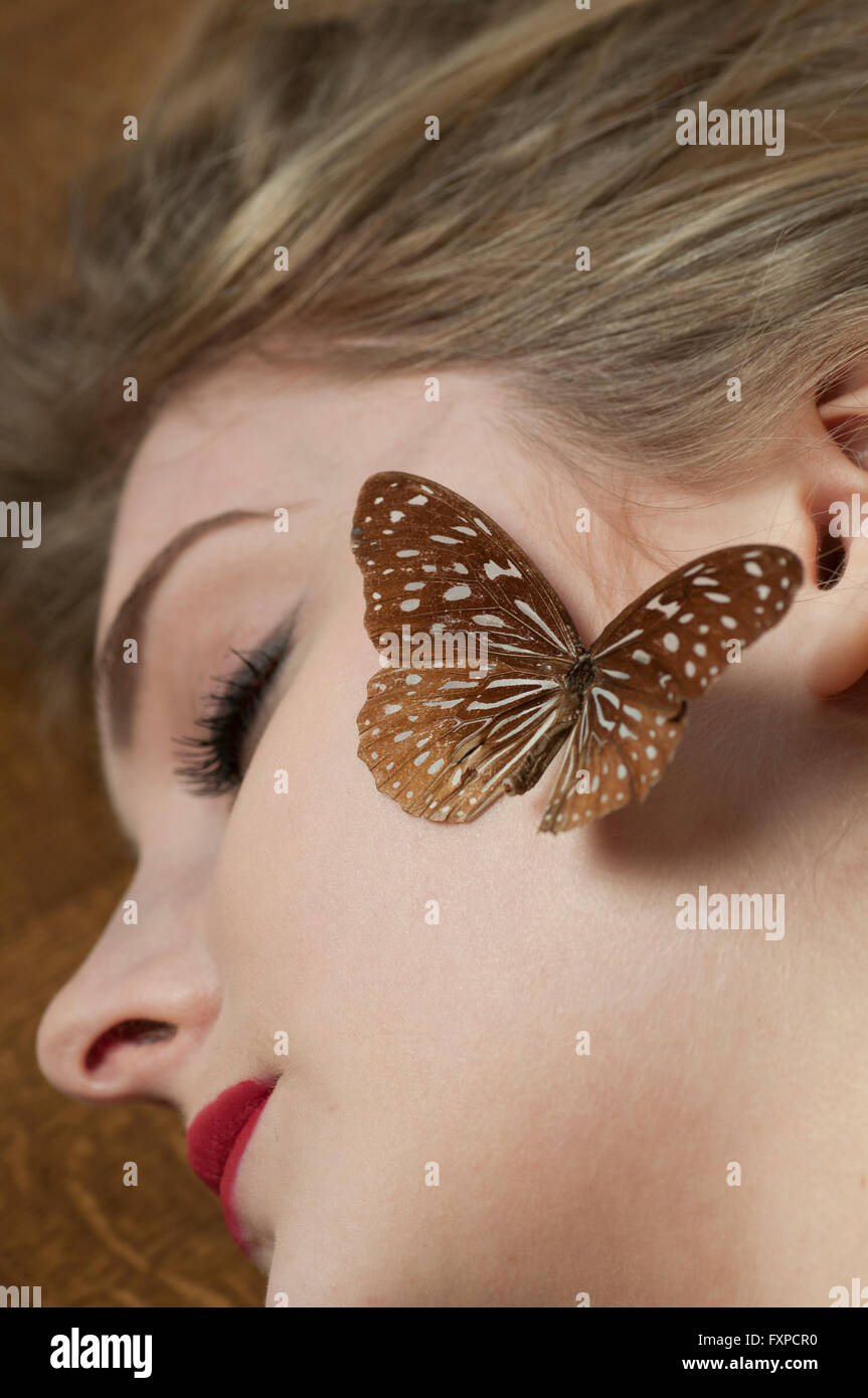 Young woman sleeping with a butterfly on her face Stock Photo