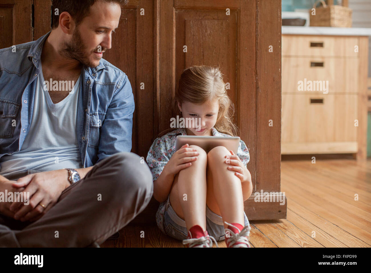 Father watching as daughter plays video game Stock Photo