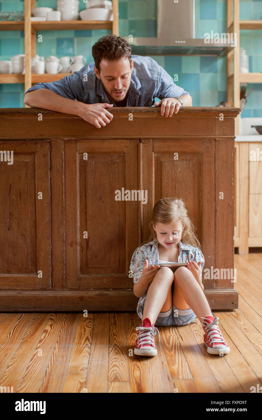 Father looking on as daughter plays video game Stock Photo
