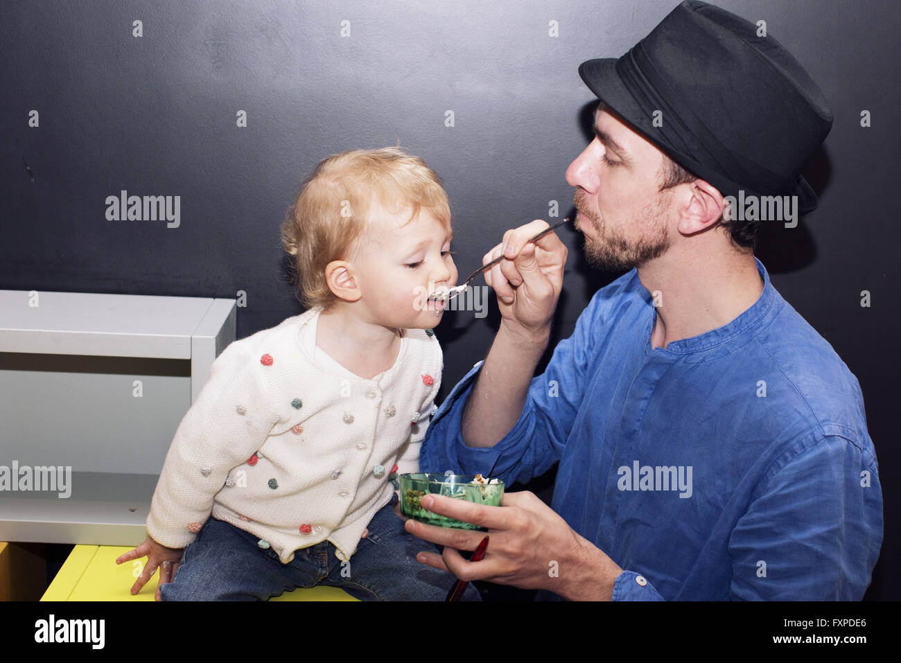 Father spoon feeding toddler Stock Photo