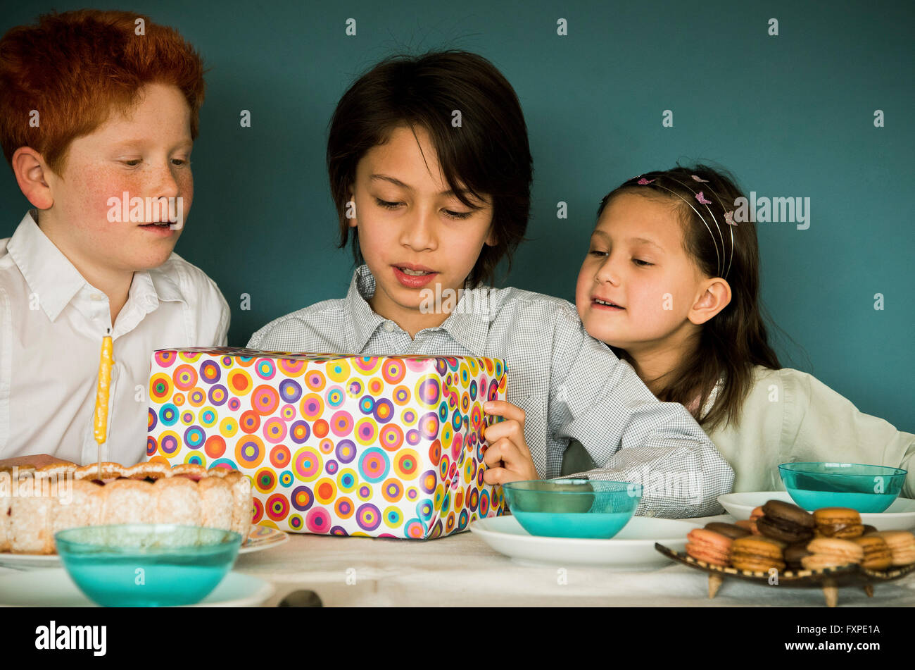 Children looking at wrapped gift at birthday party Stock Photo