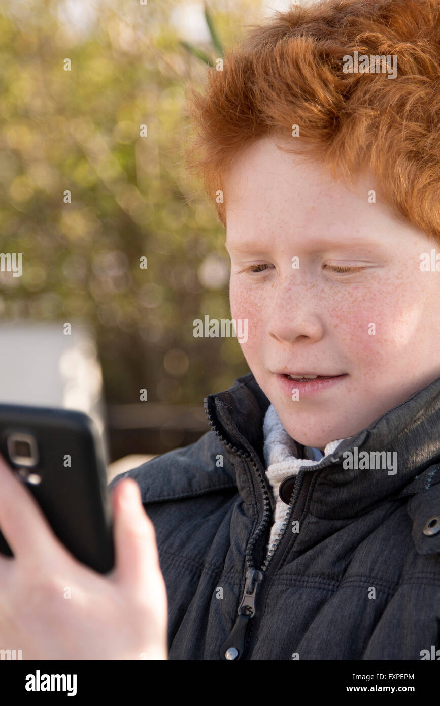 Boy using smartphone outdoors Stock Photo