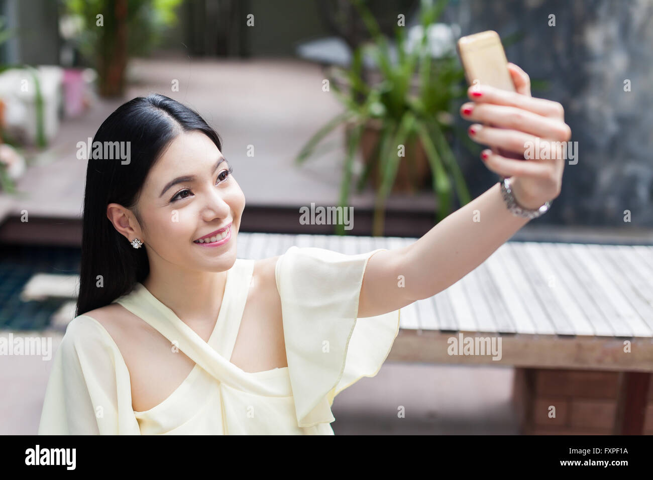 Asian woman taking a selfie with her phone in public park (focus on her ...