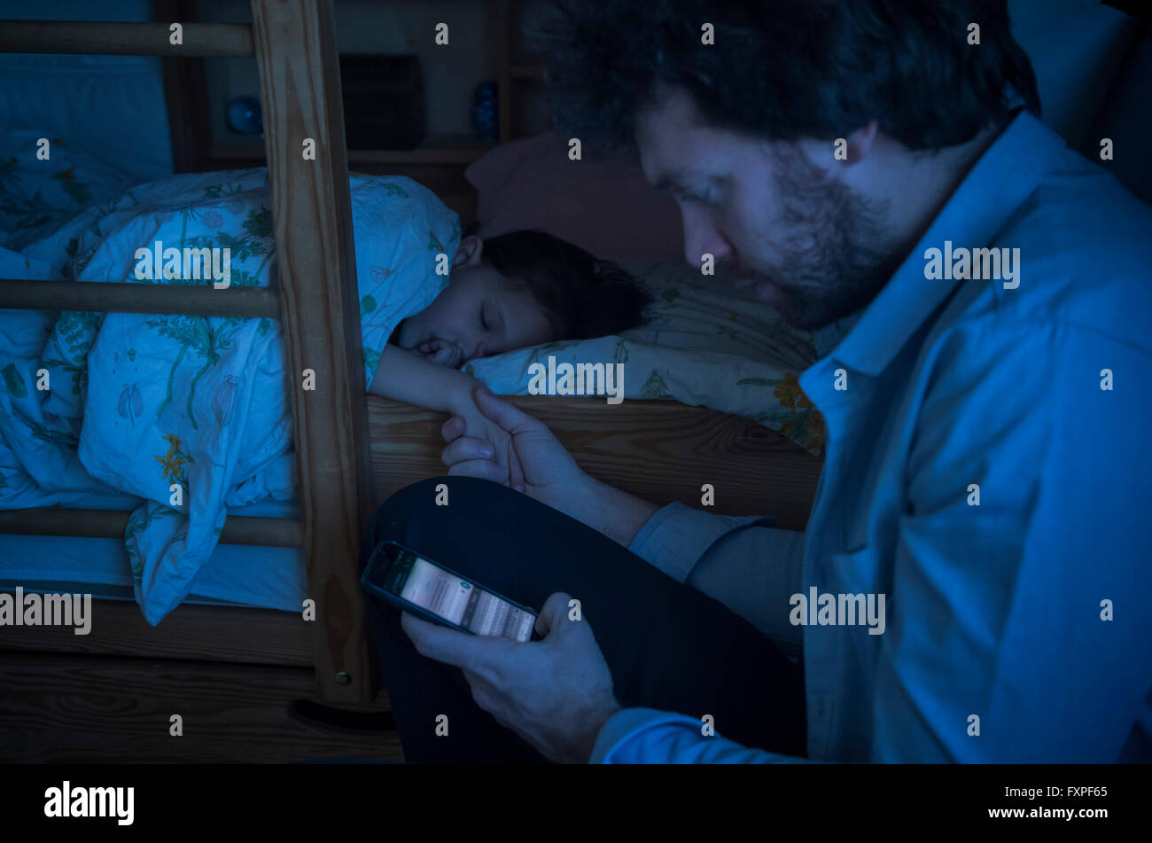 Father checking smartphone while comforting sick daughter Stock Photo