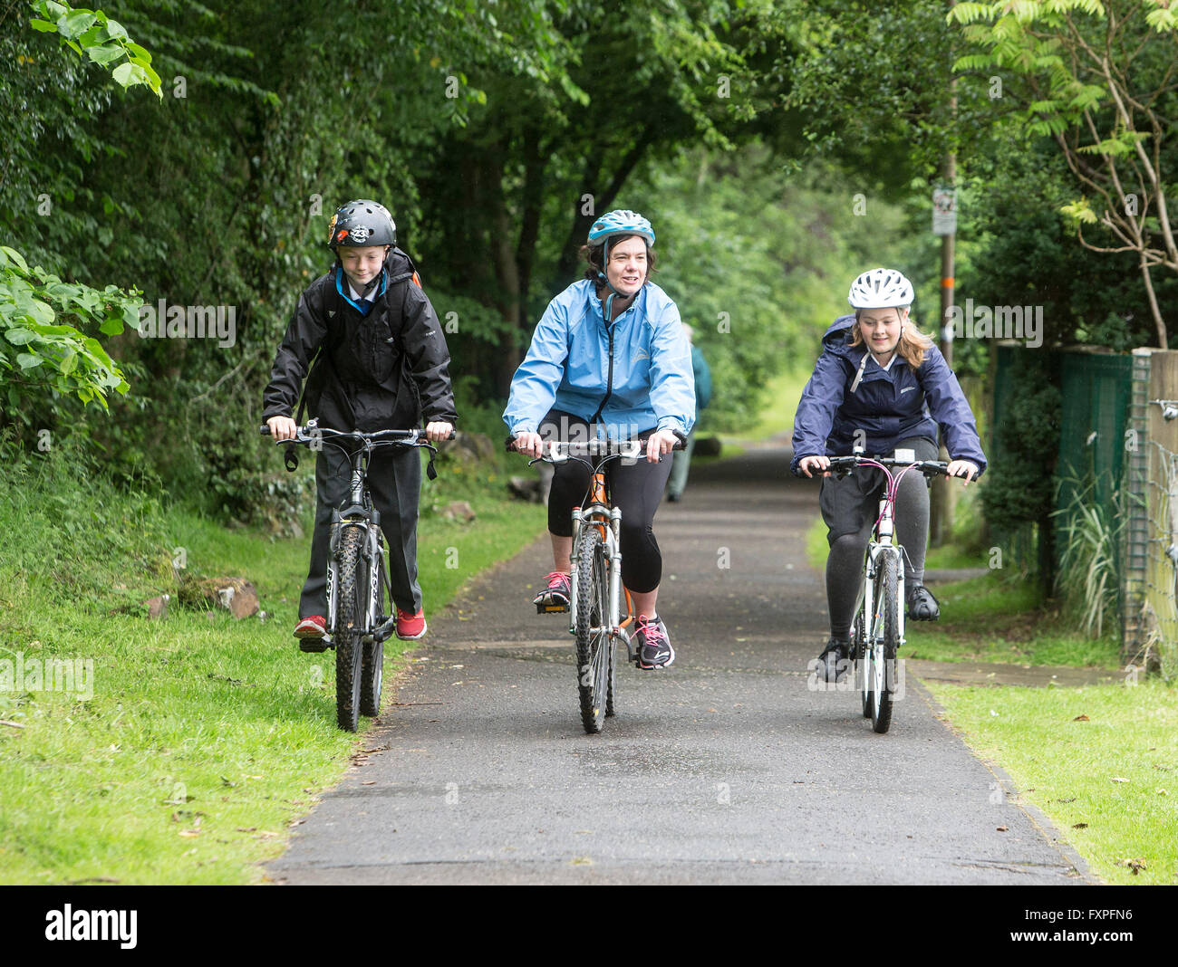 Children safely cycling to school with adult supervision on pathways Stock Photo