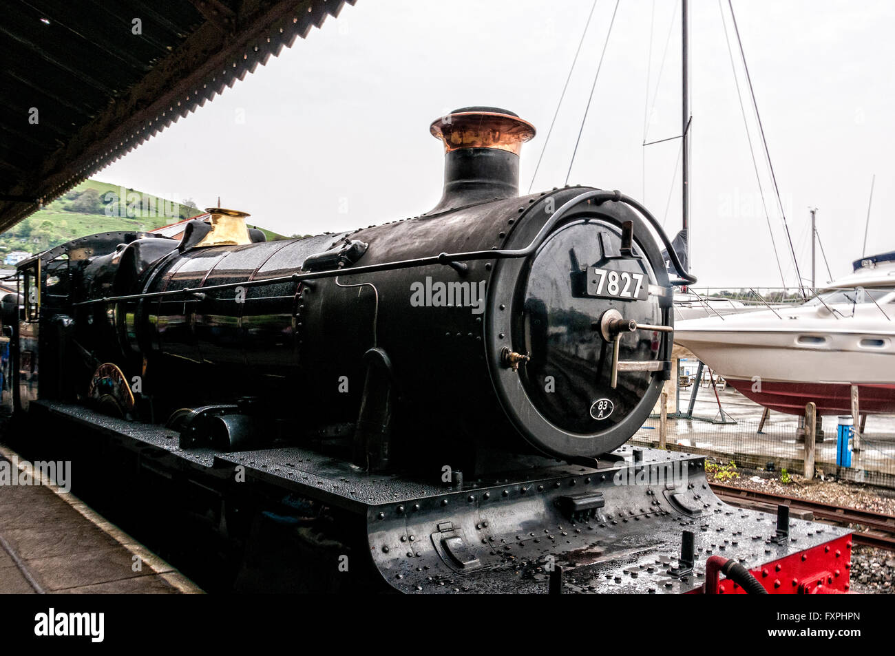 The restored steam locomotive Lydham Manor stands gleaming at the platform of Kingswear Railway Station on a damp misty day Stock Photo