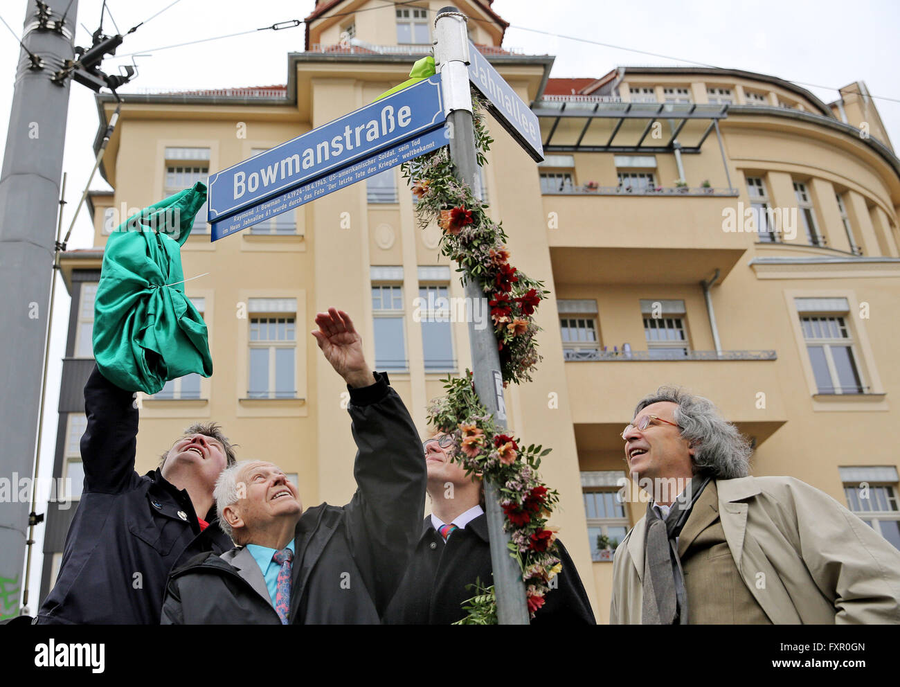 US veteran Lehman Riggs (C), comedian Meigl Hoffmann (L) and Leipzig's cultural mayor Michael Faber (R) unveil a sign for a street named after dead US soldier Bowman in front of the Capa House in Leipzig, Germany, 17 April 2016. The building, now also known as Capa House, became famous internationally through the picture 'Last man to die' by US war photographer Robert Capa. He documented how US soldier Raymond J. Bowman was shot dead on the second floor balcony on 18 April 1945 as US forces liberated Leipzig. The building was overhauled after years of decay, with an exhibition now showcasing t Stock Photo