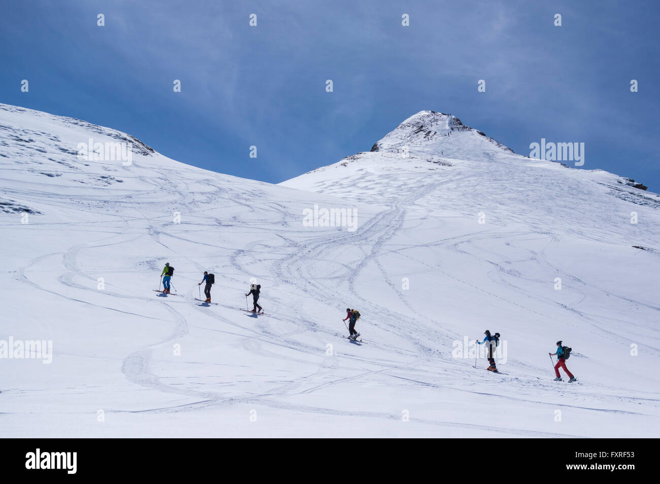 Ski mountaineers in the Swiss Alps, ascending to the summit of Rossstock mountain on a sunny day. Spilau, Uri, Switzerland. Stock Photo