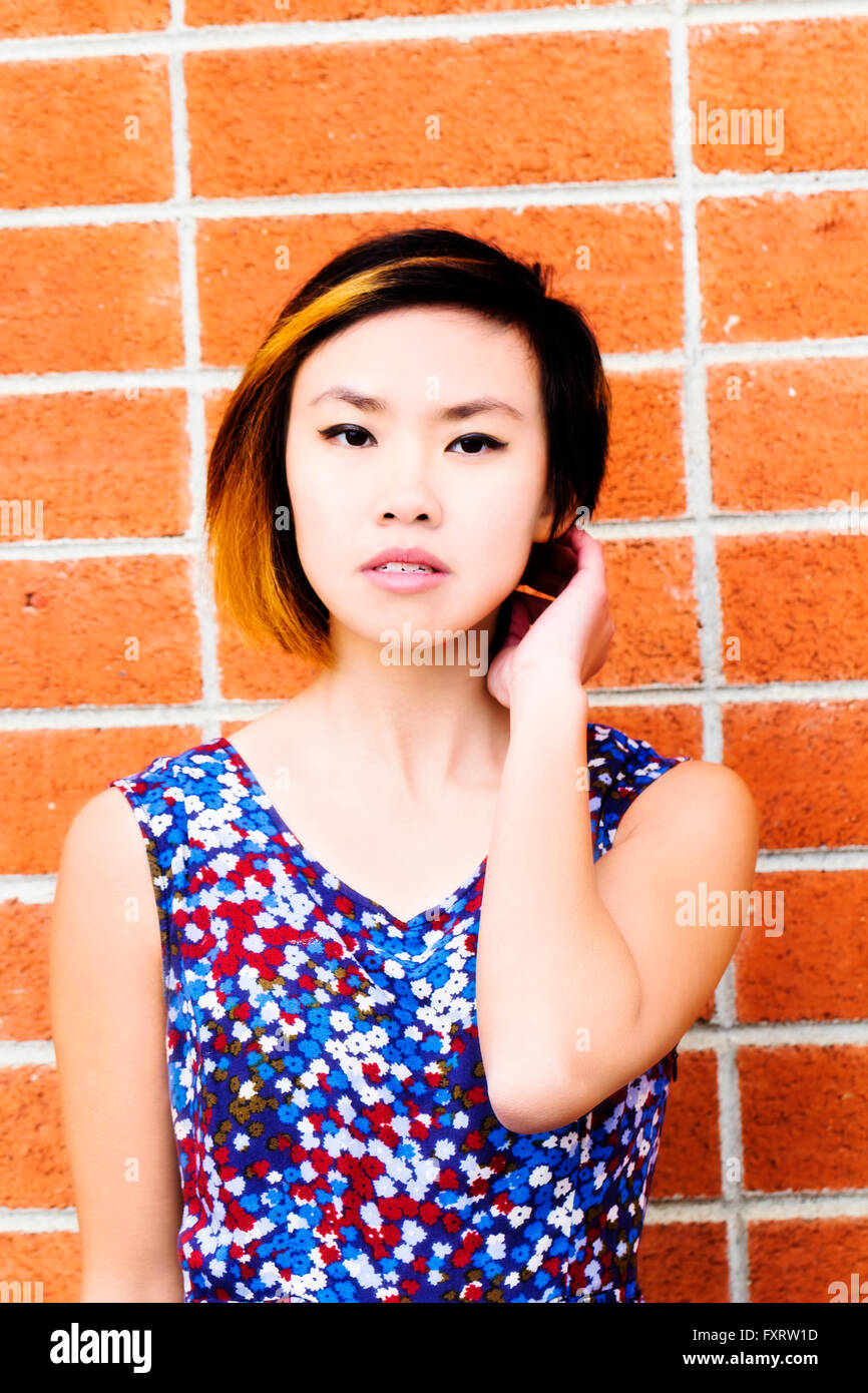 Portrait Asian American Woman Against Brick Wall Stock Photo