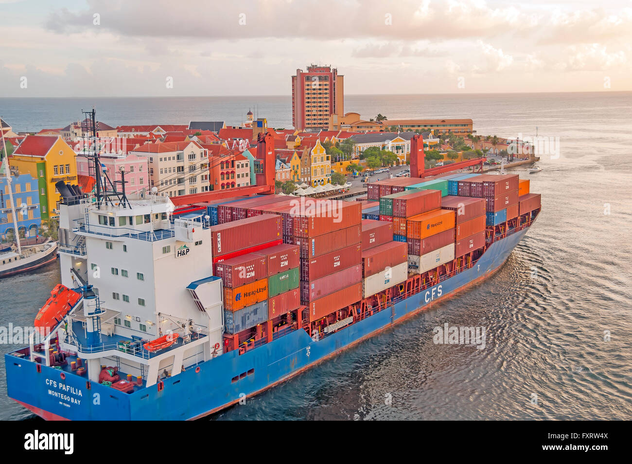 Cargo container ship travels St Anna Bay dividing Punda and Otrabanda sides of Willemstad Curacao Stock Photo