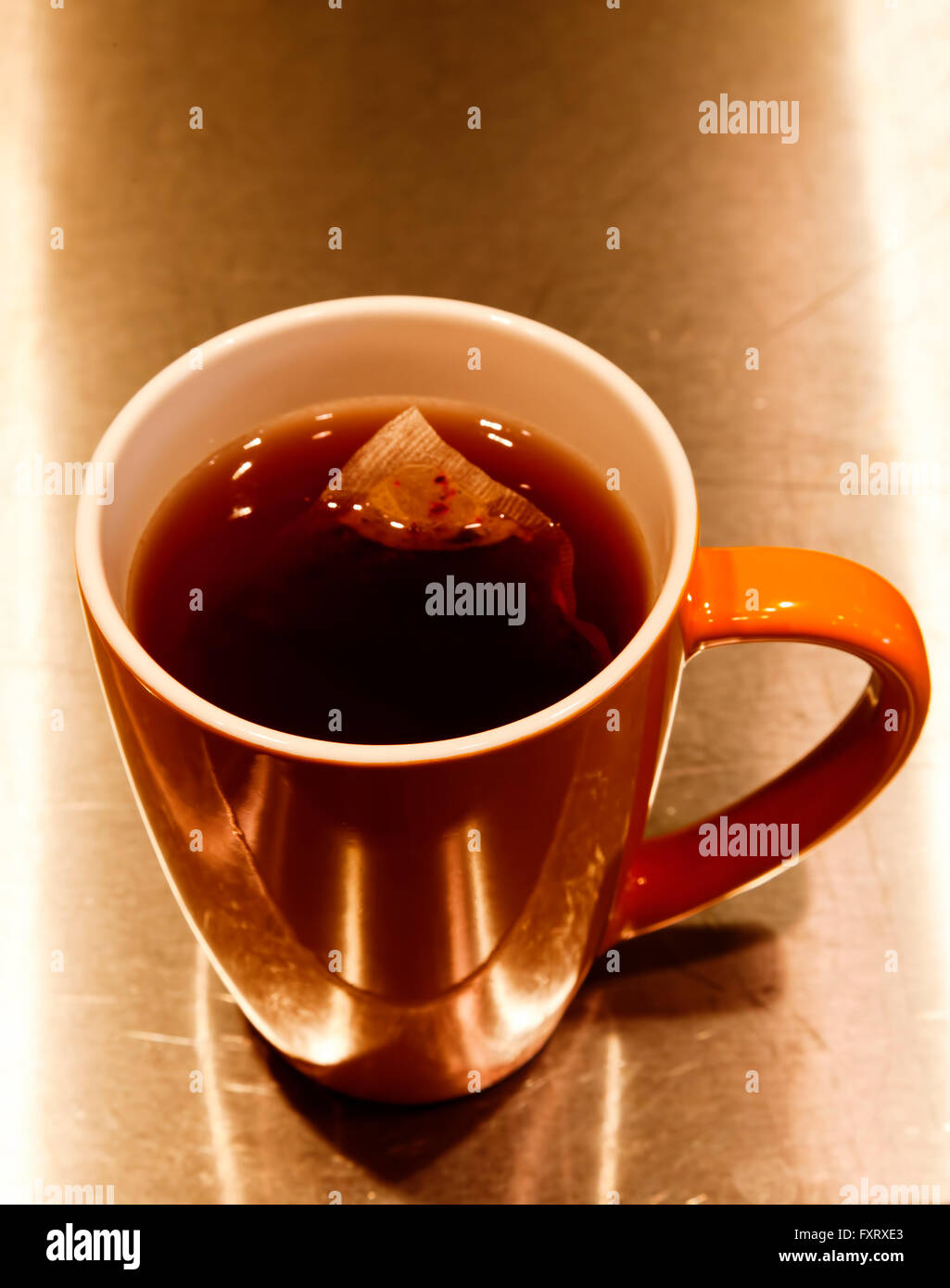 Tea Bag Steeping In Orange Cup On Metal Stove Top Stock Photo Alamy