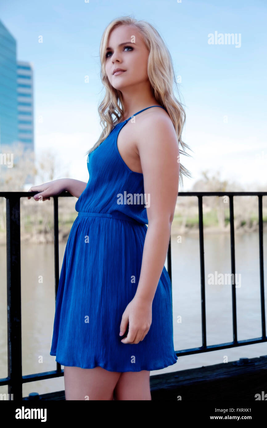 Blond Woman Outdoors Standing In Blue Dress Near River Stock Photo