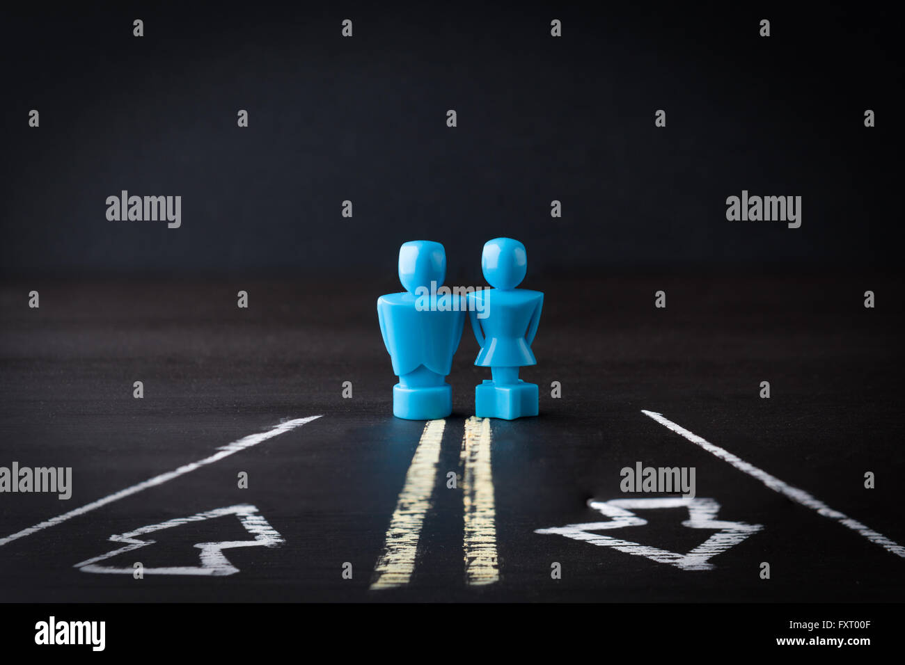 Male and female figurines standing on a two way lane road. Relationship and communication concept. Stock Photo