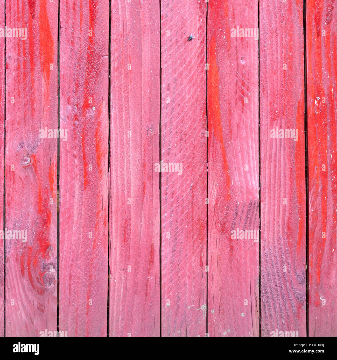 vertical planks of faded red painted worn planks on square piece of fence or door Stock Photo