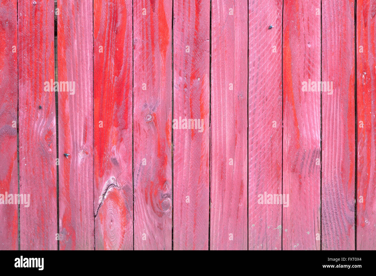 vertical planks of faded red painted worn planks on horizontal piece of fence or door Stock Photo