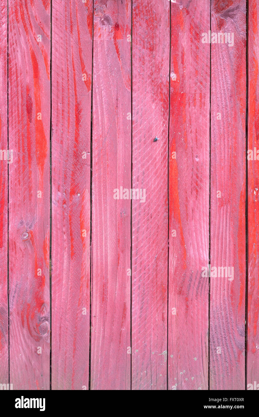 vertical planks of faded red painted worn planks on fence or door Stock Photo