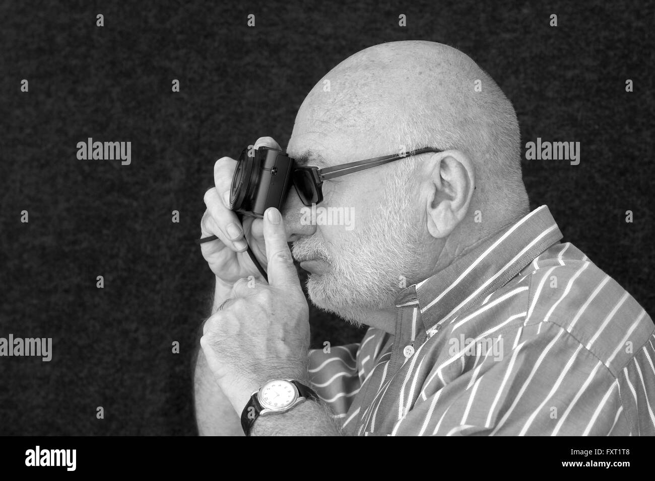 An old man taking a photograph in black and white. Stock Photo