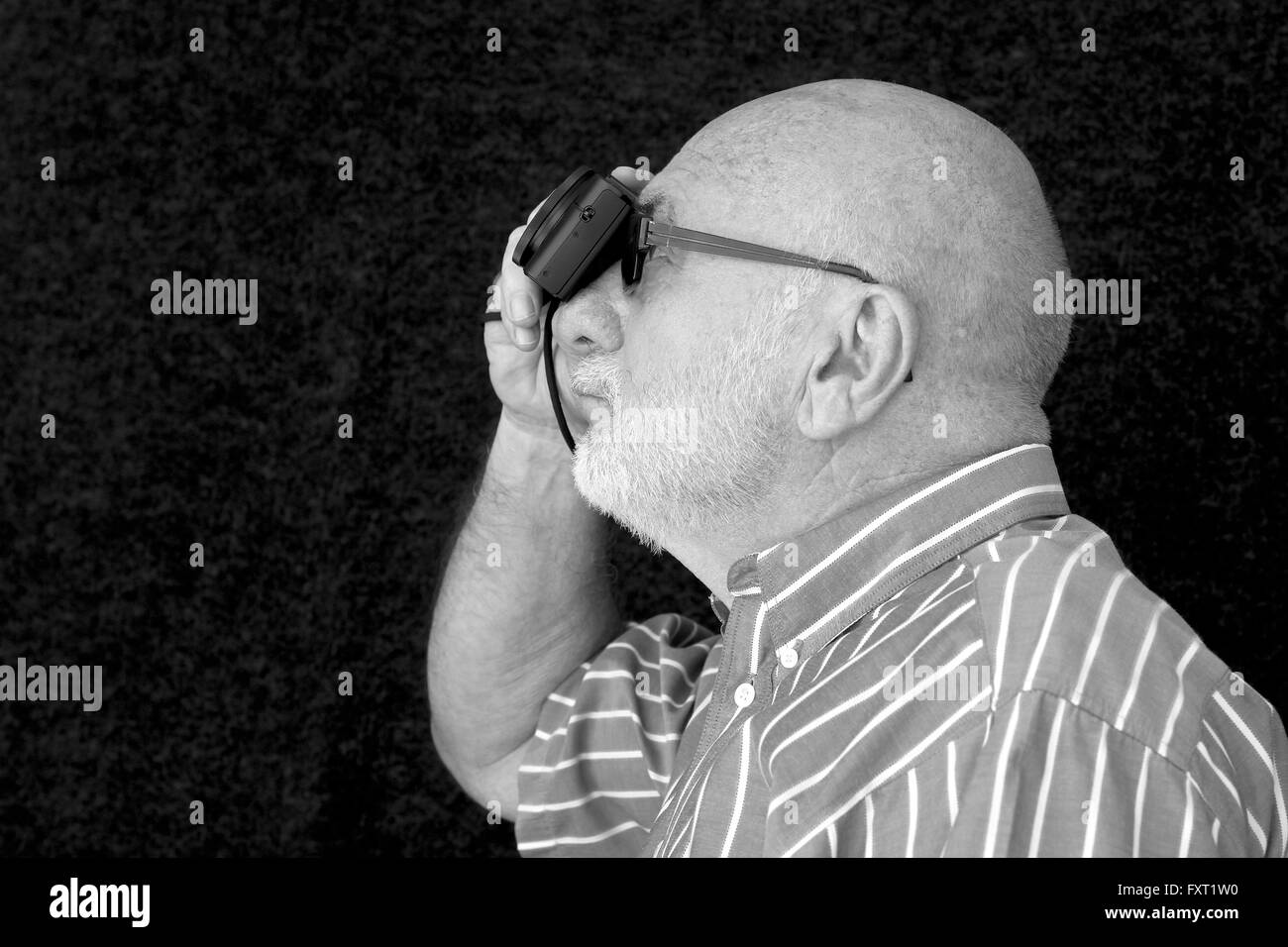 An old man taking a photograph in black and white. Stock Photo