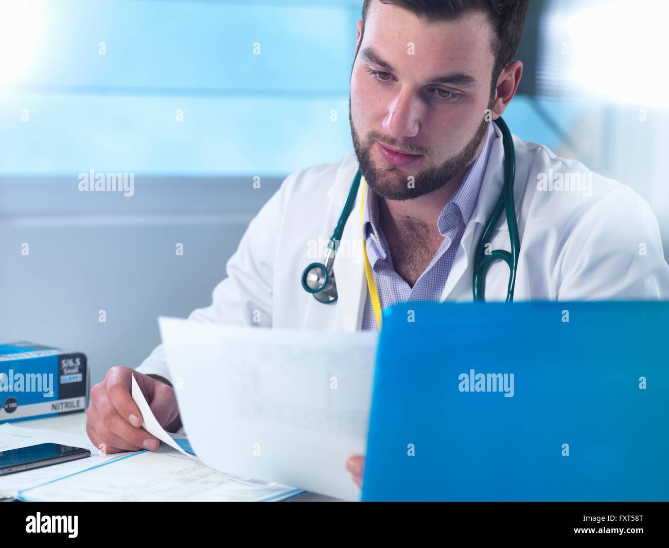 Junior doctor reading medical records in clinic Stock Photo