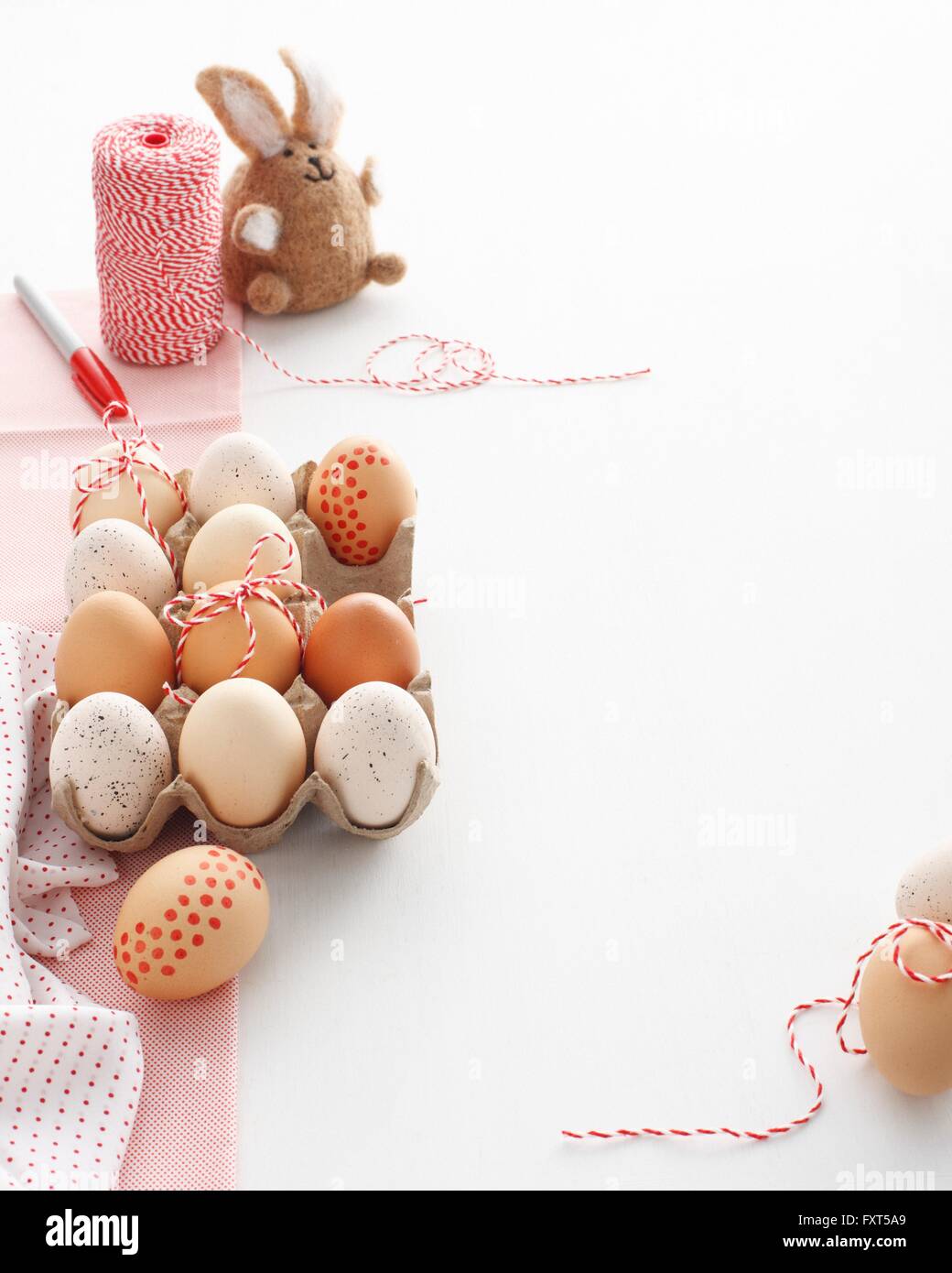 Carton of home decorated easter eggs and easter bunny on white table Stock Photo