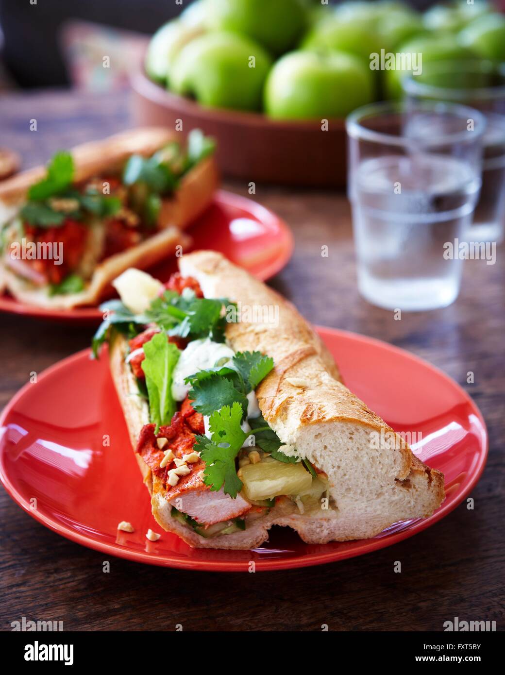 Plates of tandoori chicken baguettes on wooden table Stock Photo