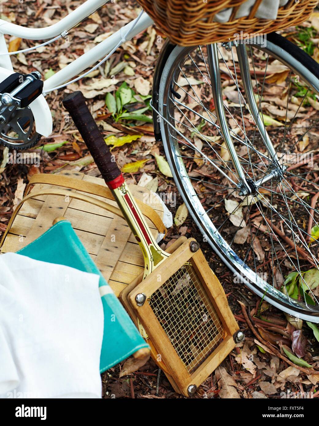 Bicycle, picnic basket and tennis racket on autumn leaf covered ground