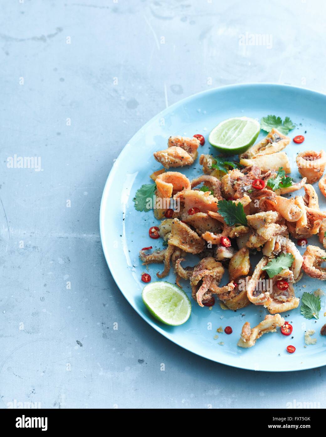 Overhead view of salt and pepper chilli squid garnished with lemon and