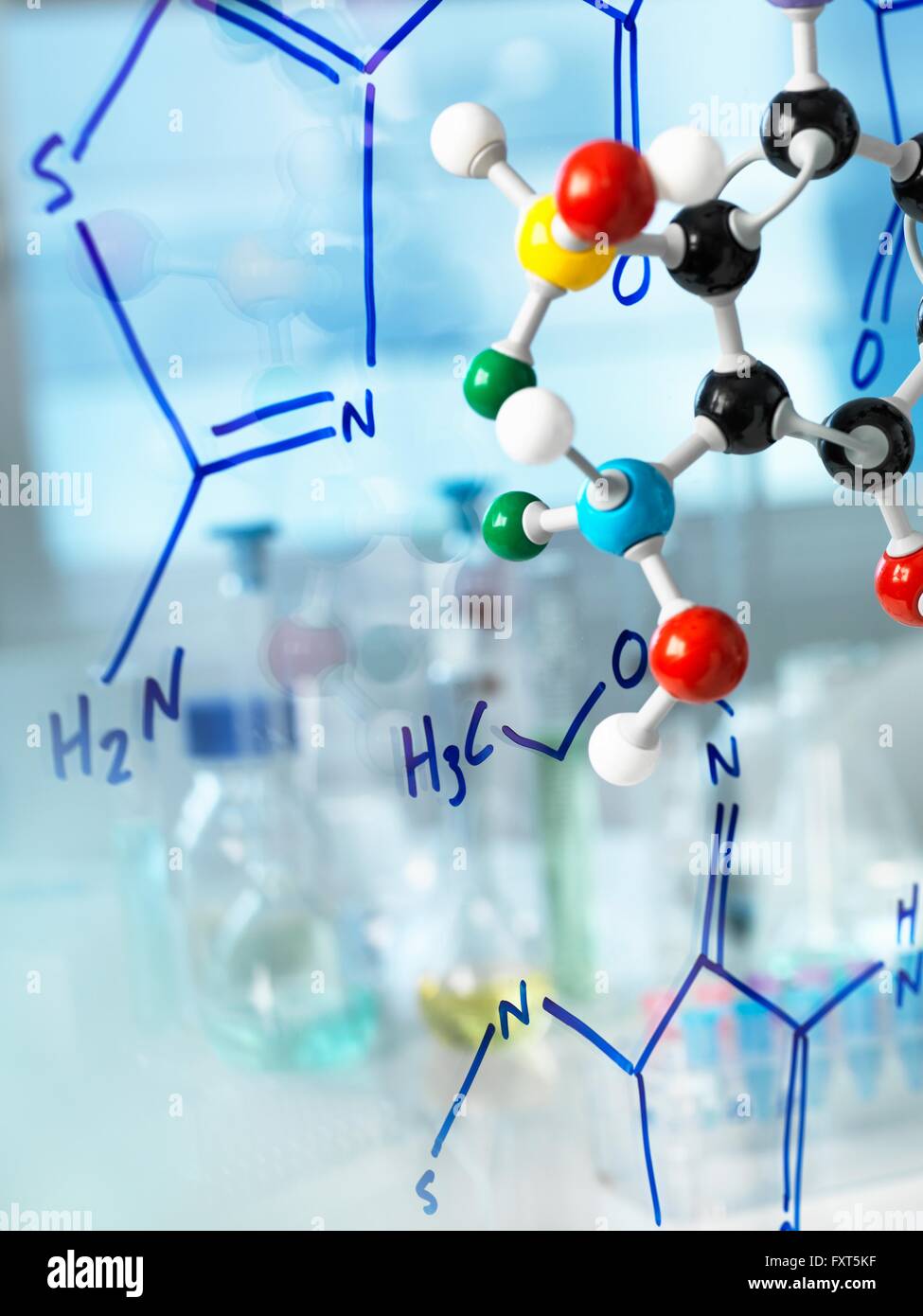 Ball and stick molecular model with formula of new drug written on glass Stock Photo